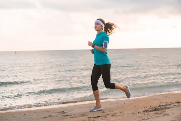 Jeune fille fit courir sur la plage au lever du soleil le matin