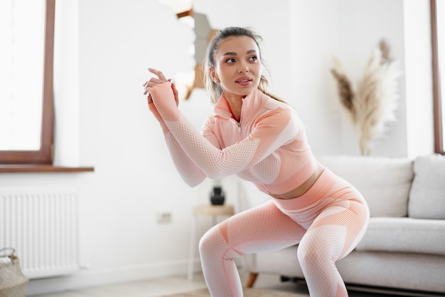 Jeune fille fitness faisant des exercices de sport dans son salon à la maison