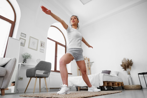 Jeune fille fitness faisant des exercices de sport dans son salon à la maison