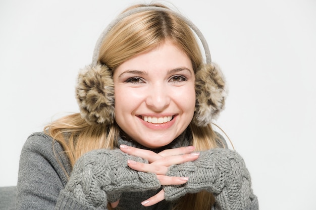 Jeune fille sur fond blanc dans un casque de fourrure en riant