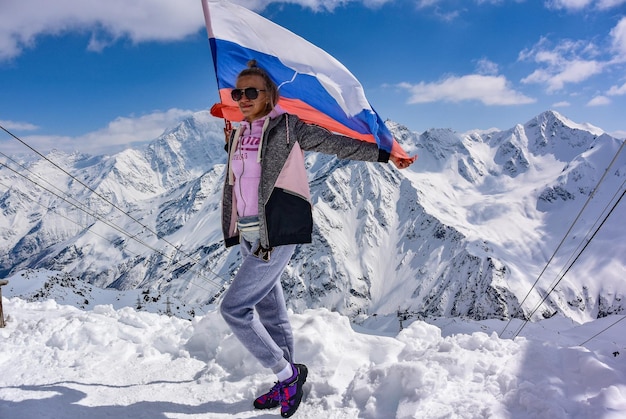 Jeune fille sur fond de montagnes enneigées et le drapeau de la Russie Elbrus 25 avril 2019