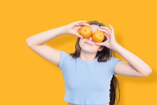 Jeune fille sur fond orange couvrant ses yeux avec deux fruits orange Fruit riche en vitamine c