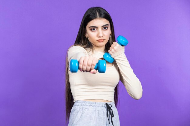 Une jeune fille en forme se tient sur fond violet et s'entraîne Photo de haute qualité