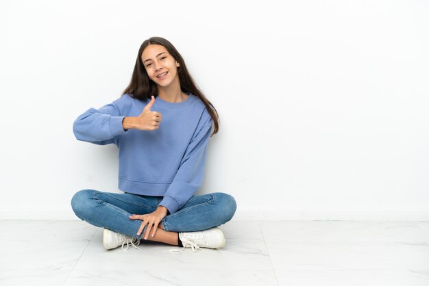 Jeune fille française assise sur le sol donnant un geste du pouce vers le haut