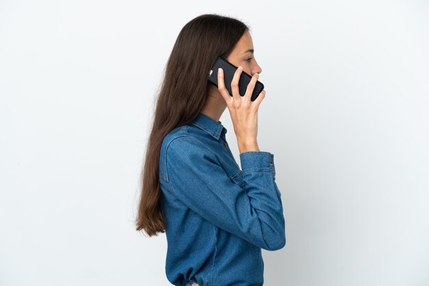 Jeune fille française isolée sur fond blanc en gardant une conversation avec le téléphone mobile avec quelqu'un