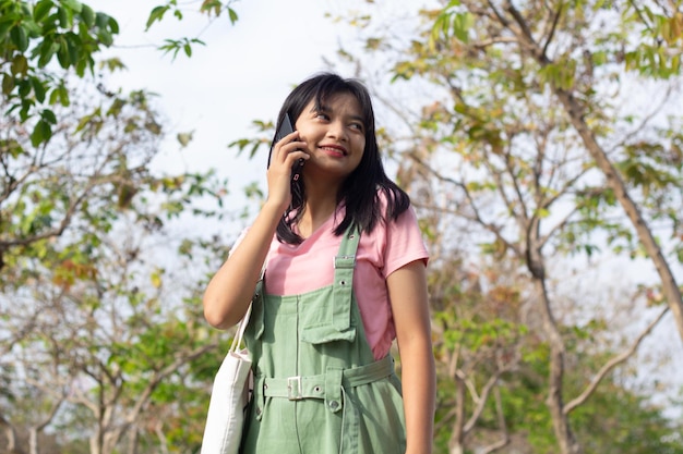 Jeune fille gaie à l'aide d'un téléphone portable et tenant un concept de style de vie de livre