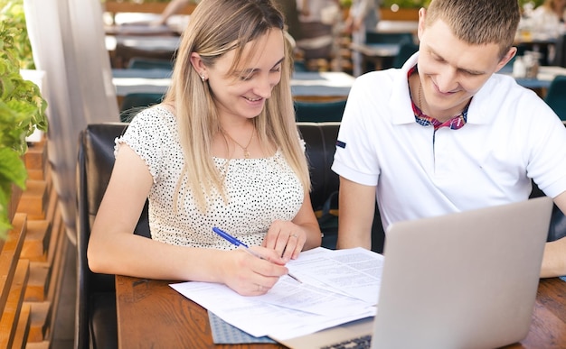 Photo une jeune fille avec un gars signe des documents assis dans un café