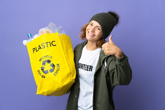 Jeune fille géorgienne tenant un sac plein de bouteilles en plastique à recycler avec les pouces vers le haut parce que quelque chose de bien s'est passé