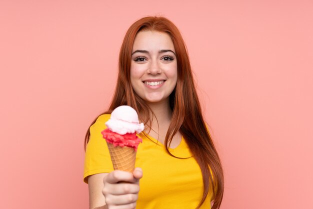 Jeune fille avec une glace au cornet sur un mur isolé avec une expression heureuse