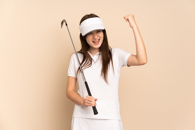 Jeune fille de golfeur isolée sur beige célébrant une victoire