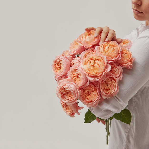 jeune fille avec un gros bouquet de roses médiatiques roses, fête des mères
