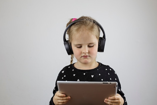 Jeune fille avec de gros écouteurs se penche sur la tablette