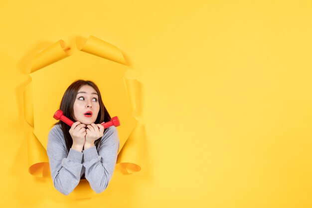 Jeune fille avec des haltères rouges sur fond de papier jaune exercice d'athlète