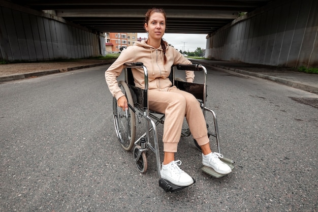Une jeune fille handicapée est assise dans un fauteuil roulant dans la rue. Le concept d'un fauteuil roulant, d'une personne handicapée, d'une vie pleine, d'une personne paralysée, handicapée, de soins de santé.