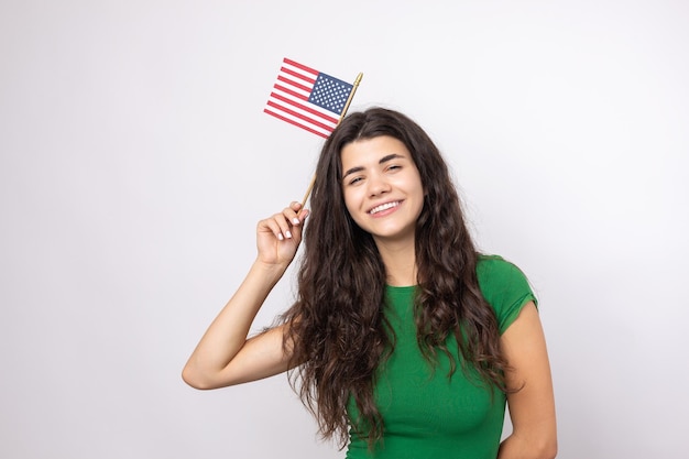 Une jeune fille heureuse avec un sourire sur son visage tient un drapeau américain dans ses mains Symbole de patriotisme et de liberté