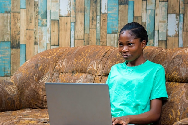 Jeune fille hipster africaine noire travaillant à domicile assise sur un canapé à l'aide d'un ordinateur portable femme d'affaires faisant des achats en ligne à la maison