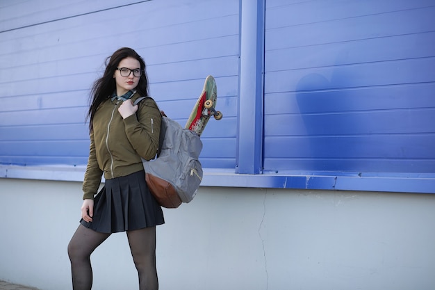 Une jeune fille hipster fait du skateboard. Copines de filles pour une promenade en ville avec une planche à roulettes. Sports de printemps dans la rue avec une planche à roulettes.