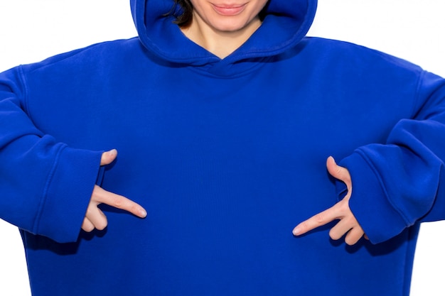 Jeune fille hipster portant un sweat à capuche bleu pointant vers la poitrine avec les deux mains