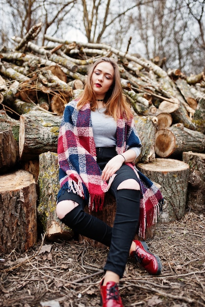 Jeune fille hipster porter sur la couverture contre les souches en bois sur bois.