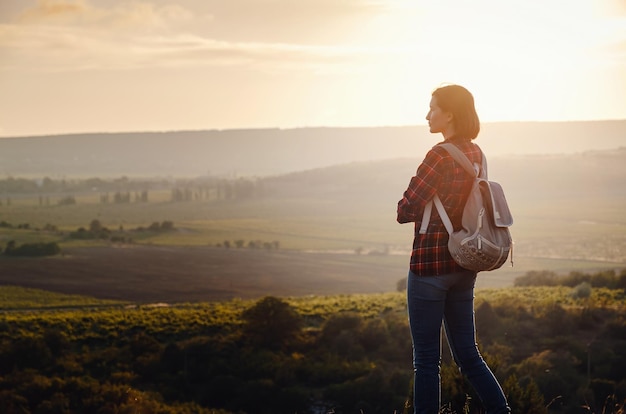 Jeune fille hipster profiter du coucher du soleil sur le point de vue Voyage femme avec sac à dos