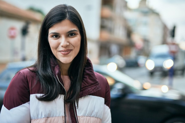 Jeune fille hispanique souriante heureuse debout à la ville.