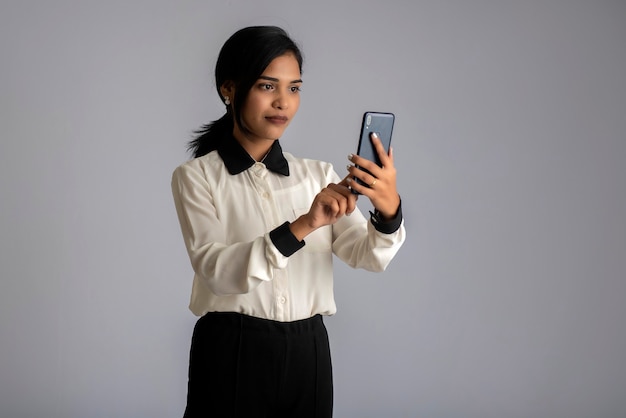 Jeune fille indienne à l'aide d'un téléphone mobile ou d'un smartphone sur un mur gris