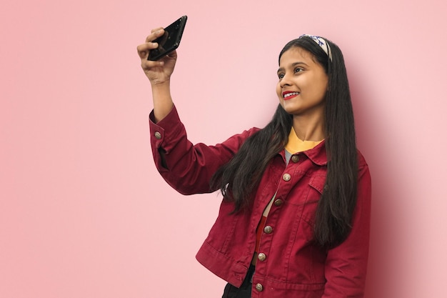 Jeune fille indienne souriante posant isolé prenant selfie photo sur téléphone portable maquette espace de copie