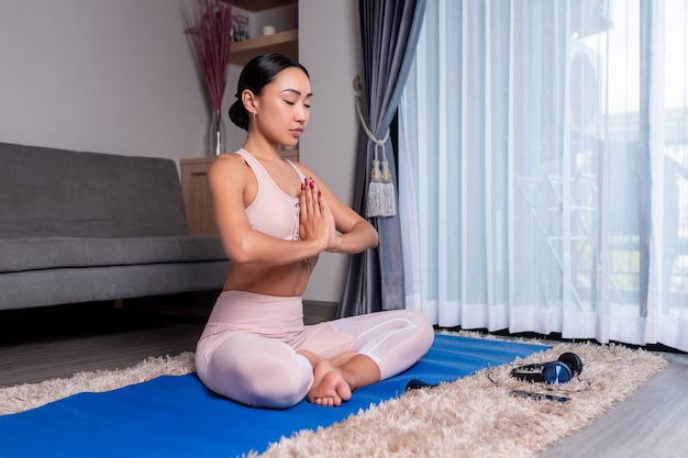 Une jeune fille interraciale prend soin de son corps et pratique le yoga à la maison