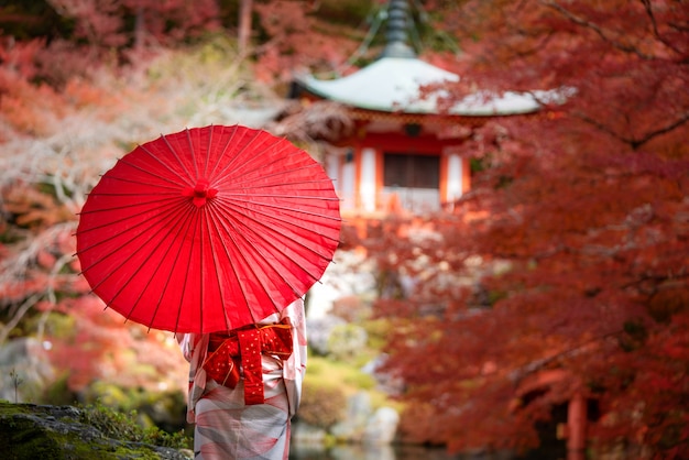 Jeune fille japonaise voyageur en robe kimino traditionnelle debout dans le temple Digoji avec pagode rouge et feuille d'érable rouge en saison d'automne à Kyoto, au Japon.