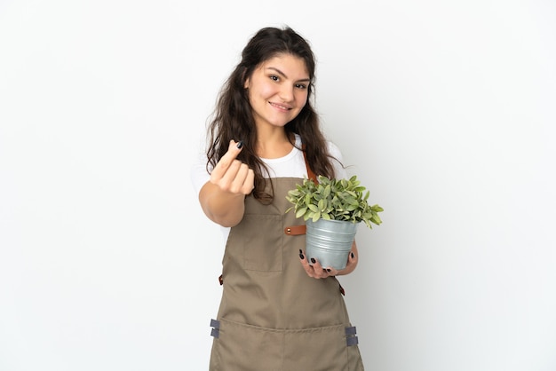 Jeune fille de jardinier russe tenant une plante isolée faisant un geste d'argent