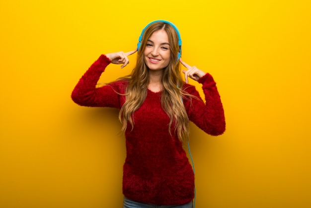 Jeune fille sur jaune vif, écouter de la musique avec des écouteurs