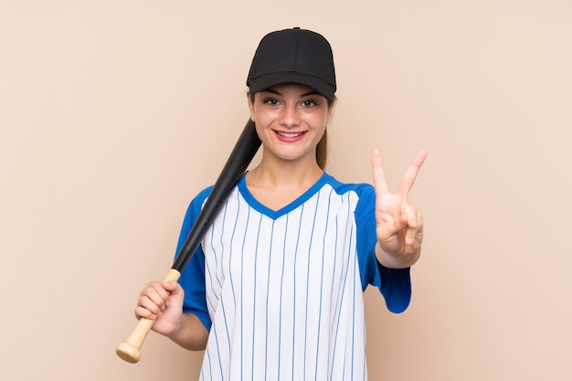 Jeune fille jouant au baseball souriant et montrant le signe de la victoire