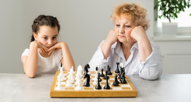 Jeune fille jouant aux échecs avec grand-mère ensemble à la maison.