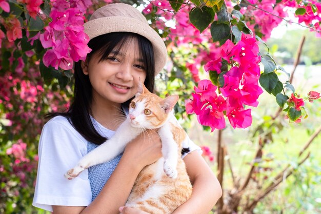 Jeune fille jouant avec un chat debout sous l'arbre à fleurs