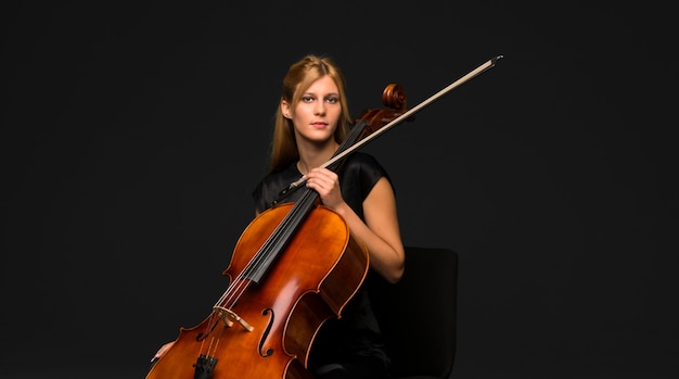 Jeune fille jouant du violoncelle sur fond noir isolé