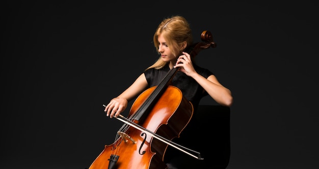 Jeune fille jouant du violoncelle sur fond noir isolé