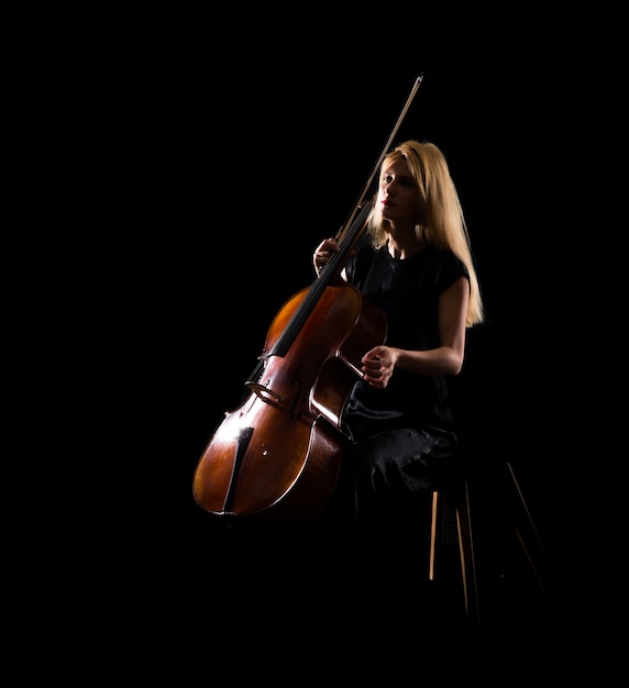 Jeune fille jouant du violoncelle sur fond noir isolé