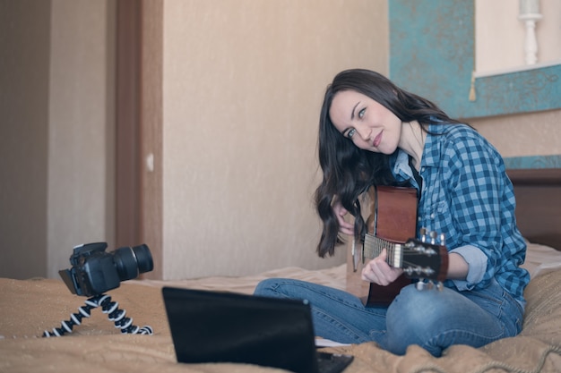 Jeune fille jouant de la guitare acoustique dans la chambre