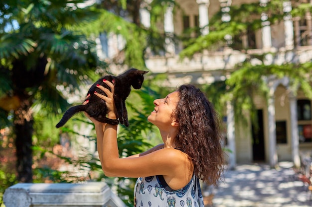 Une jeune fille joue avec un chaton noir qu'elle a trouvé dans la rue