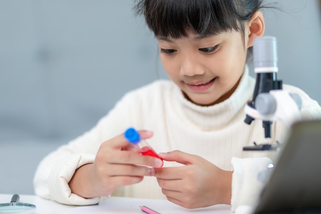 Une jeune fille joue à des expériences scientifiques pour l'enseignement à domicile