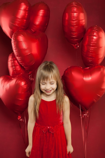 Une jeune fille joyeuse avec des ballons sur fond rouge