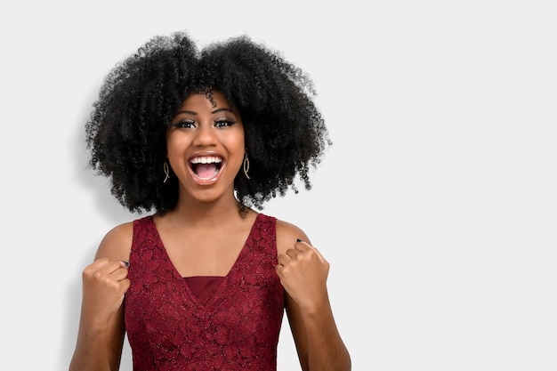 Une jeune fille joyeuse et heureuse aux cheveux afro s'avère être la gagnante lève les poings fermés