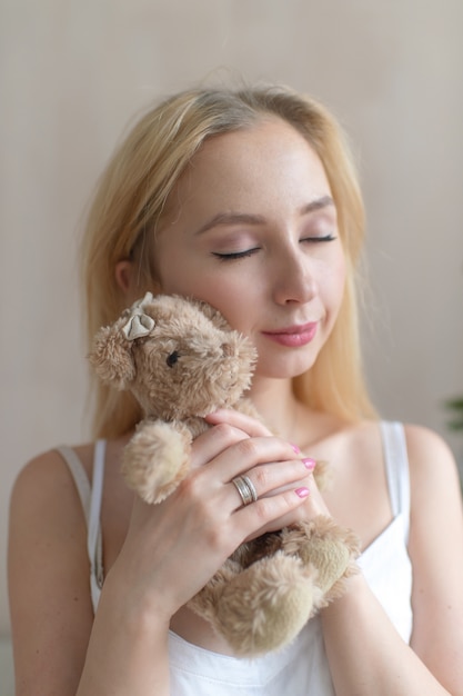 Jeune fille joyeuse en nuisette câlin ours jouet