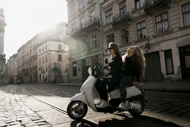 Jeune fille joyeuse avec scooter dans la ville européenne