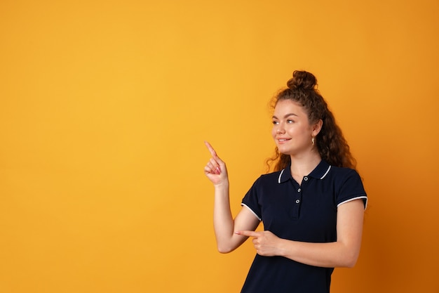 Jeune fille joyeuse souriante pointer du doigt pour copier l'espace