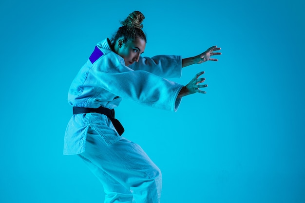 Jeune fille judiste professionnel isolé sur fond bleu studio en néon