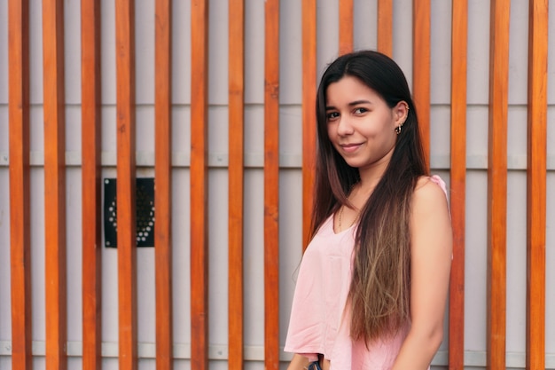 Jeune fille latina porte des vêtements décontractés et les cheveux longs rit à l'extérieur. femme souriante, amusant