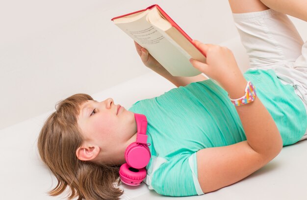 Une jeune fille lit un livre sur le canapé à la maison