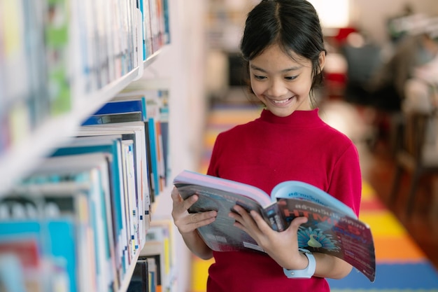 Photo une jeune fille lit un livre dans une bibliothèque.