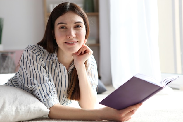 La jeune fille lit un livre à la maison